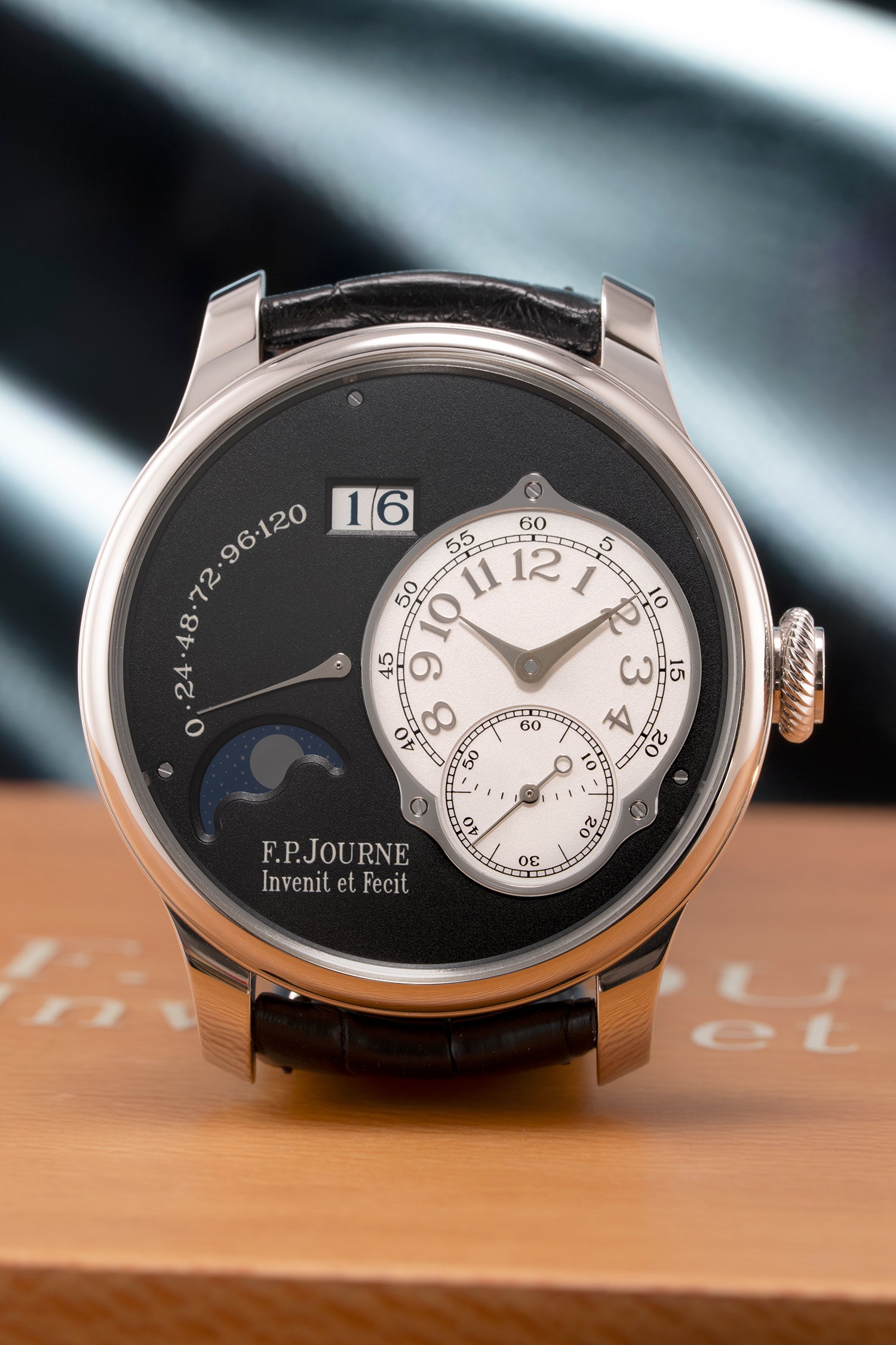 Luxury watch with detailed face and brand name on a wooden surface.
F.P. journe, black. 