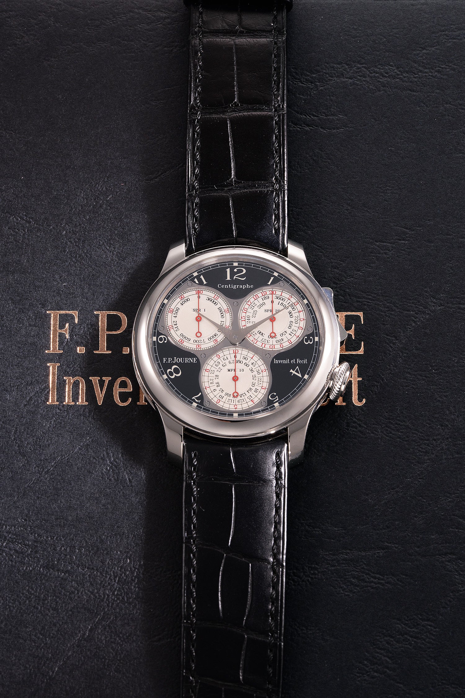 Luxury watch with black leather strap on a dark background.
F.P. journe, black.